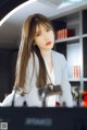 A woman in a white suit sitting at a desk.