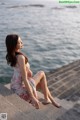 A woman sitting on the edge of a pier by the water.