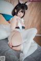 A woman in a bunny costume sitting on a bed.