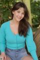 A woman in a blue cardigan sitting on a tree trunk.