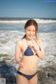 A woman in a blue bikini standing in the ocean.