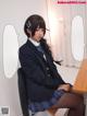 A woman in a school uniform sitting at a desk.