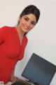 A woman in a red dress sitting at a desk with a computer.