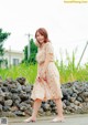 A woman standing in front of a stone wall.