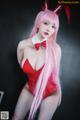 A woman in a red bodysuit with pink hair and a bow tie.
