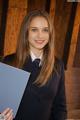 A woman in a suit and tie holding a folder.